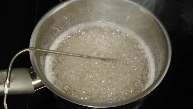 Une casserole d'eau bouillante avec des bulles sur une cuisinière : caramel