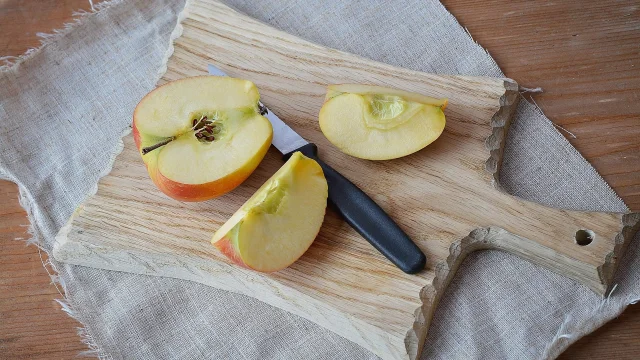 Tranches de pomme sur une planche en bois avec un couteau