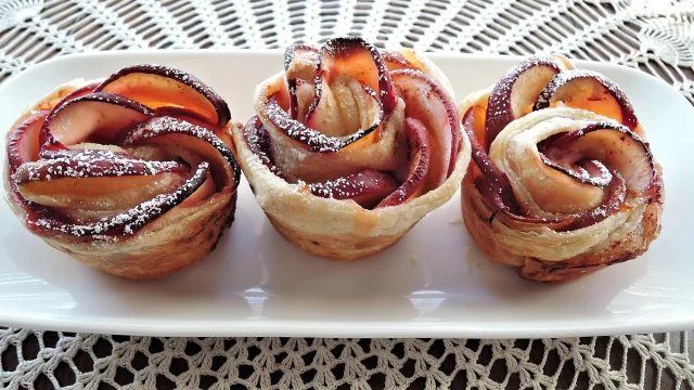 Trois pâtisseries en forme de roses faites avec des pommes et du sucre glace