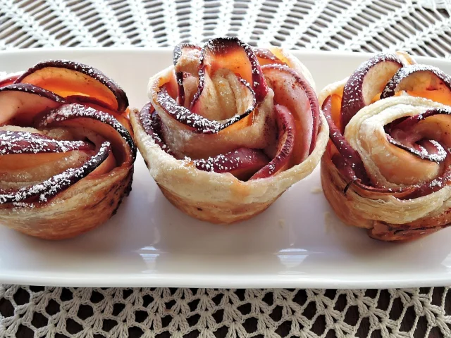 Trois pâtisseries en forme de roses faites avec des pommes et du sucre glace