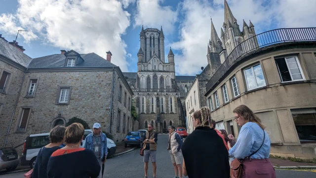 Groupe de personnes écoutant un guide devant la cathédrale de Coutances