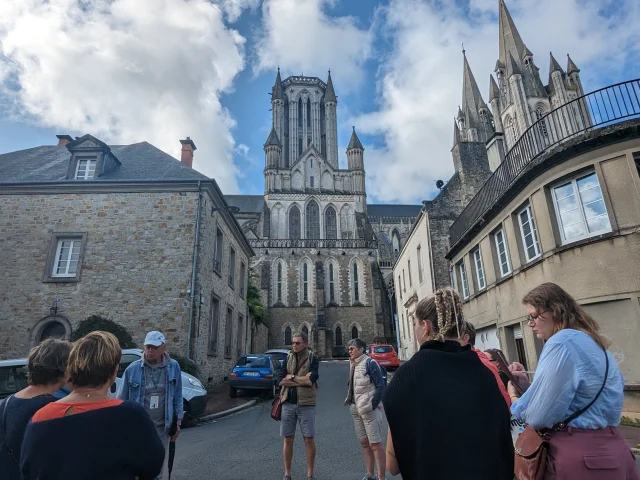 Groupe de personnes écoutant un guide devant la cathédrale de Coutances