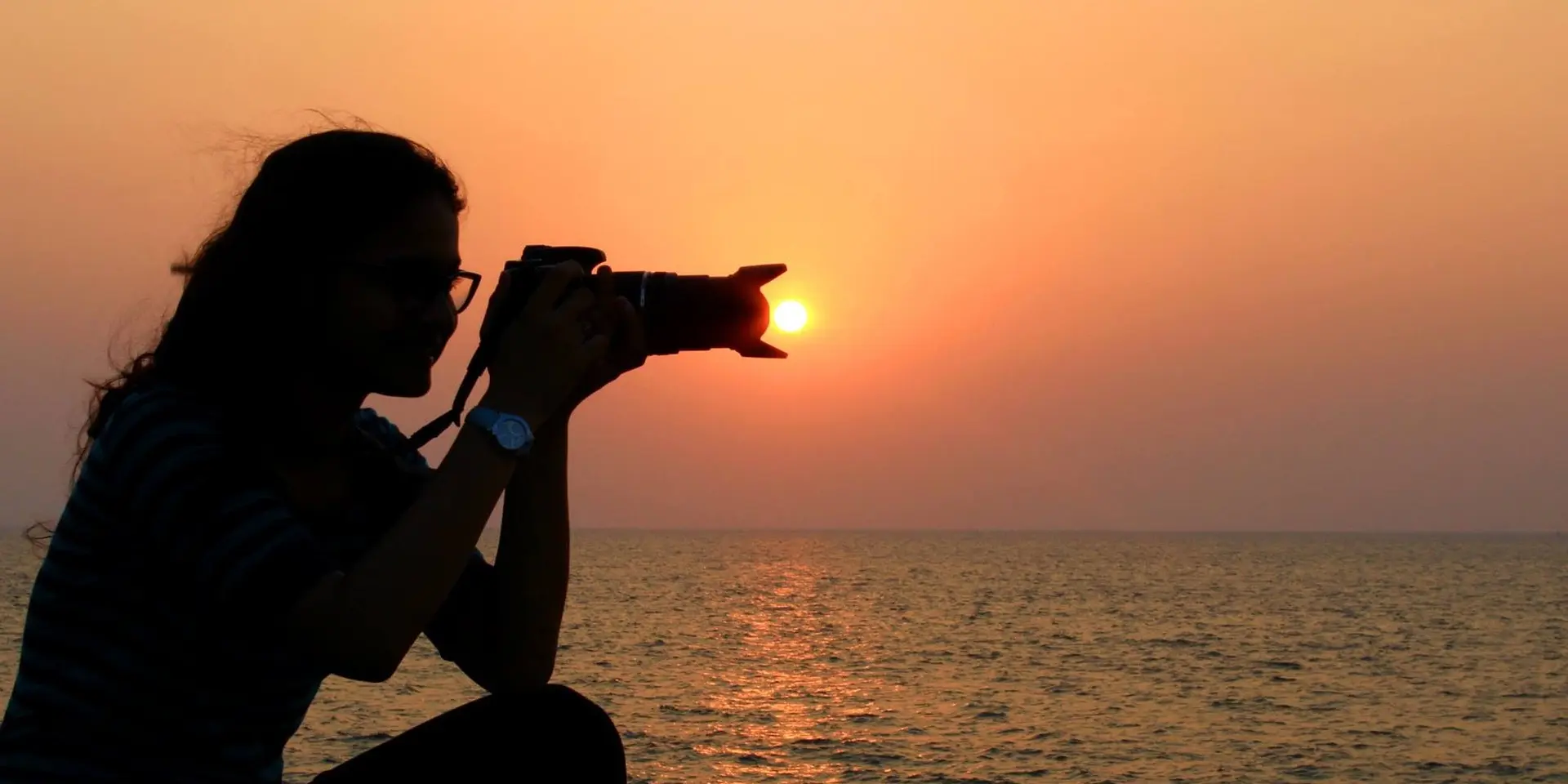 Une personne prend une photo du coucher de soleil sur la plage