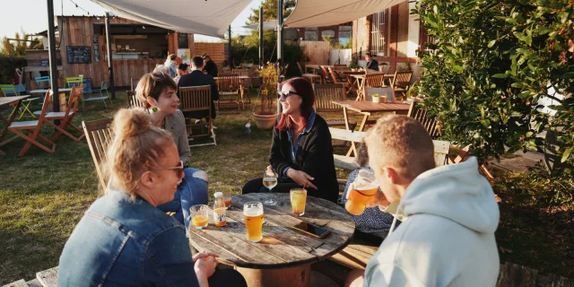 Groupe d'amis assis autour d'une table en bois en terrasse à la petite Gare de Regnéville sur Mer