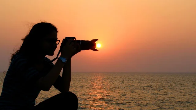 Une personne prend une photo du coucher de soleil sur la plage