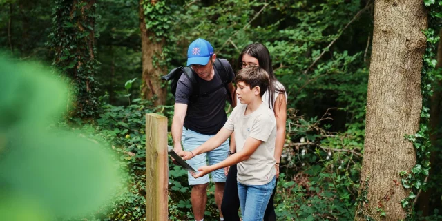 Un homme, une femme et un enfant marchent sur un sentier en forêt : randonnée