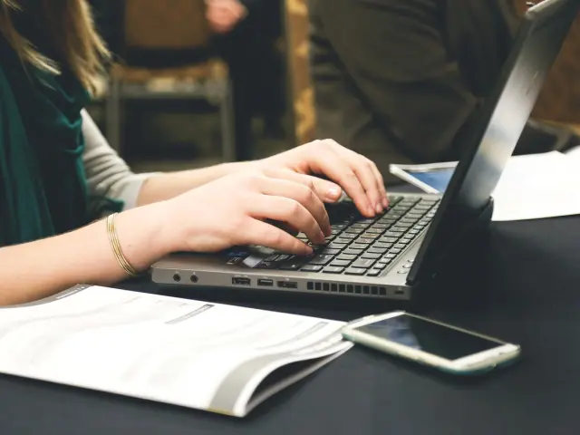 Personne utilisant un ordinateur portable avec des documents à côté