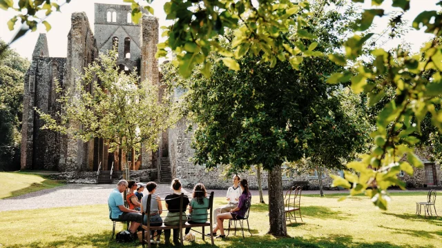 Groupe de personnes assises en cercle devant l'Abbaye de Hambye durant une visite
