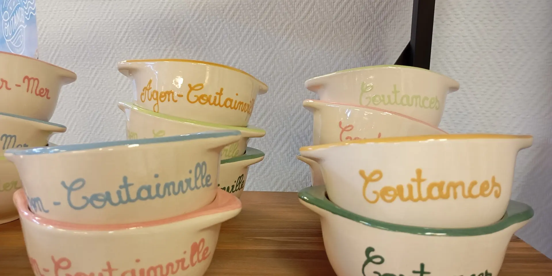 Bols empilés avec des noms de villes de Coutances mer et bocage écrits dessus