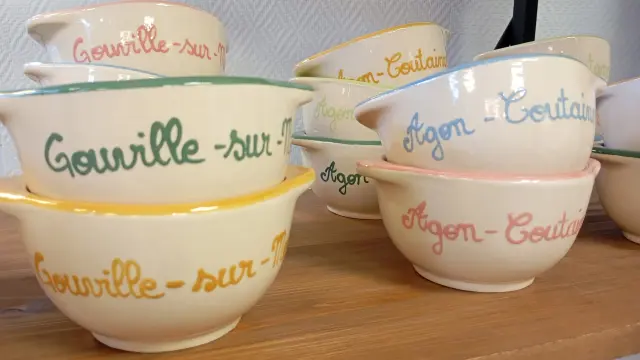 Bols empilés avec des noms de lieux écrits en différentes couleurs, les villes de Coutances mer et bocage