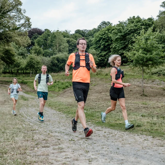 Quatre personnes courent sur un chemin de terre en pleine nature