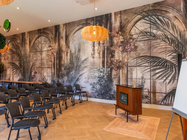Salle de réunion avec des chaises, un écran et une décoration murale tropicale : éco domaine du Plessis