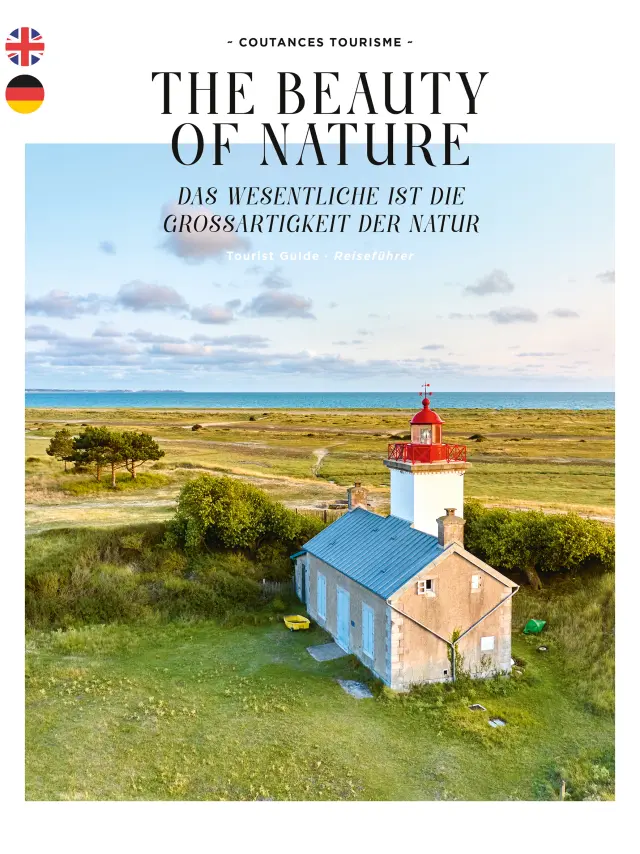 Red and white lighthouse surrounded by greenery, with a blue-roofed blue house nearby, near a body of water