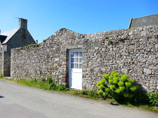 Maison en pierre avec une porte blanche dans les rues de Regnéville-sur-Mer